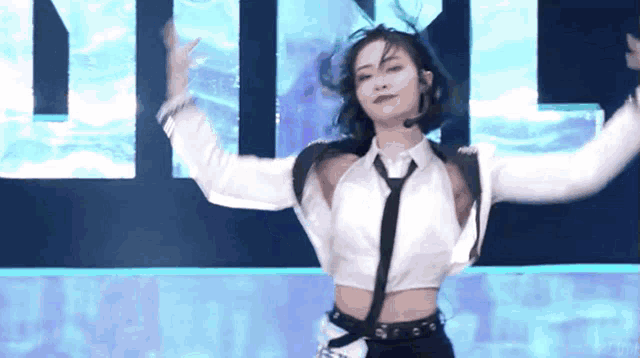 a woman in a white shirt and tie is dancing in front of a sign that says ' n ' on it