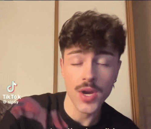 a young man with a mustache is making a funny face with his eyes closed