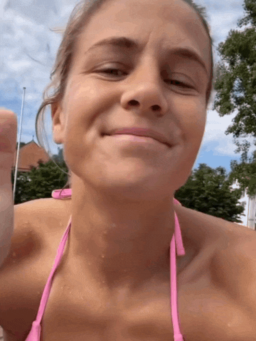 a woman in a pink bikini is smiling and giving the thumbs up