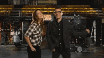 a man and a woman are dancing in front of a sign that says people 's live