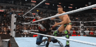 two men are wrestling in a ring and one of them is wearing a who shirt