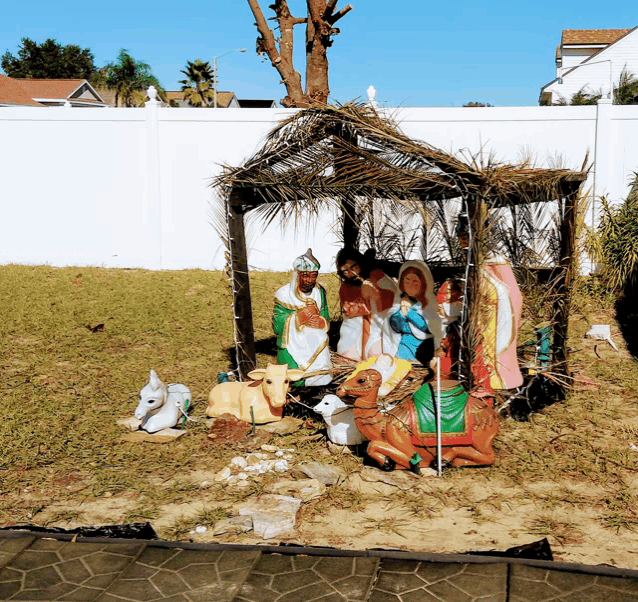 a nativity scene in a yard with a white fence behind it