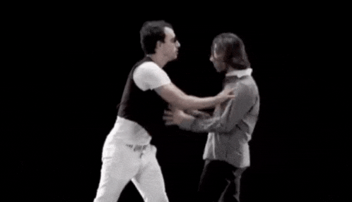 two men are dancing on a black background and one of them is wearing sunglasses