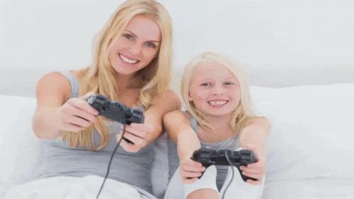 a woman and a little girl are playing a video game on a bed