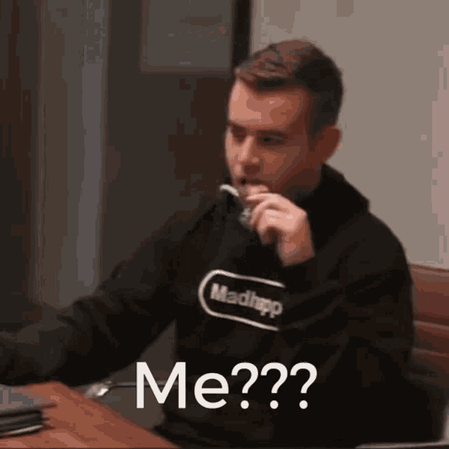 a man is sitting at a desk with a toothbrush in his mouth and the words me ?