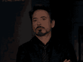 robert downey jr. is wearing a suit and tie and looking at the camera .