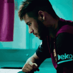 a man wearing a beko shirt sits at a table