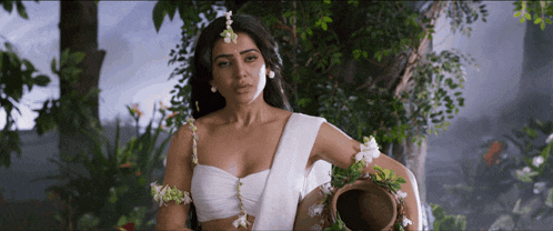 a woman in a white crop top holds a pot of water