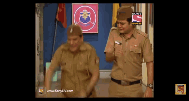 two police officers are dancing in front of a sony logo