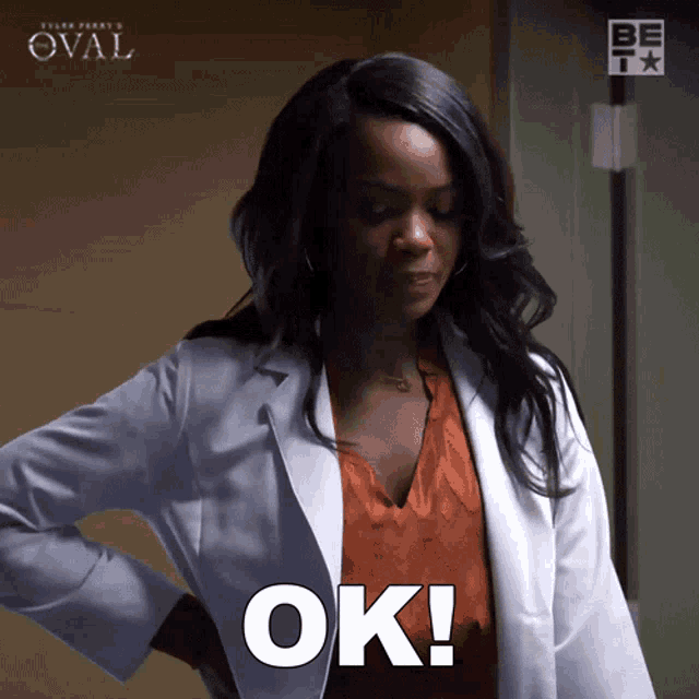 a woman in a lab coat says ok in a room