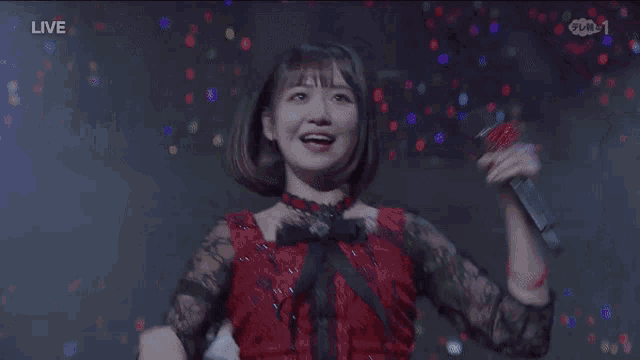 a woman in a red dress singing into a microphone with the word live on the bottom