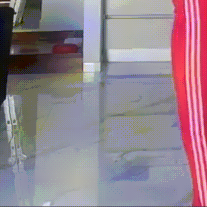 a person wearing red striped pants is standing on a tiled floor in a kitchen .