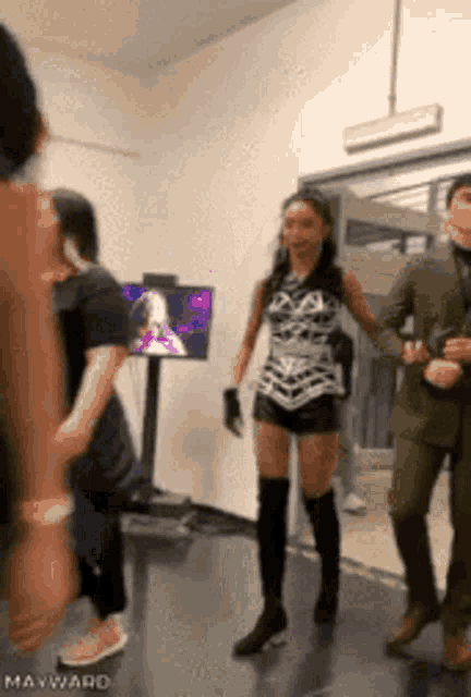 a woman in shorts and knee high boots is walking in a hallway with a man in a suit