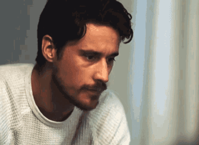 a close up of a man 's face with a white shirt on