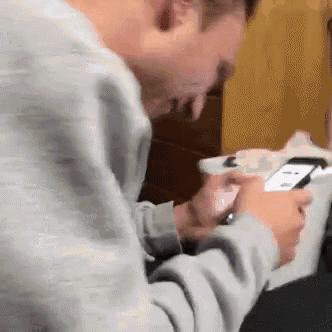 a man is looking at a cell phone while another man looks on