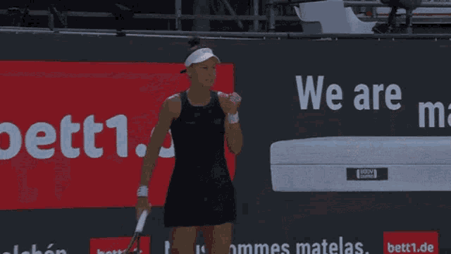 a tennis player stands in front of a sign that says we are