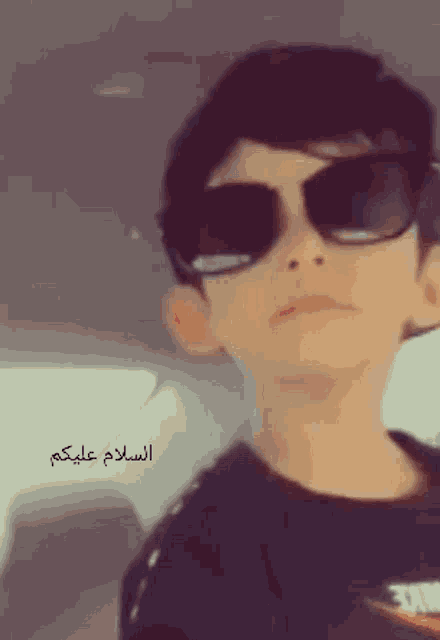 a boy wearing sunglasses and a nike shirt looks at the camera