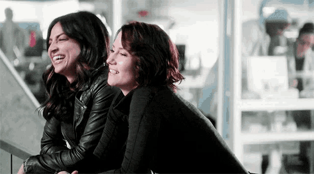 two women are sitting next to each other on the stairs and laughing .
