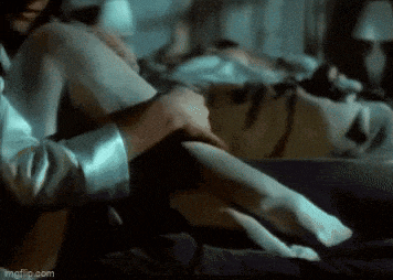a man is touching a woman 's leg in a dark room .