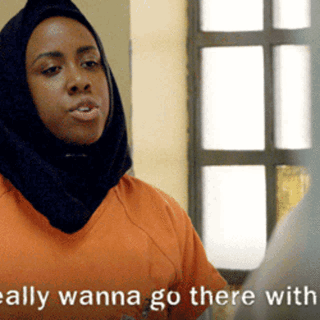 a woman wearing a black head scarf and an orange shirt says really wanna go there with