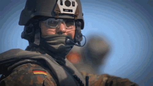 a close up of a soldier wearing a helmet and glasses with a german flag on his chest