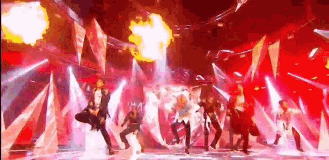 a group of people are dancing on a stage with a fire coming out of the ceiling .