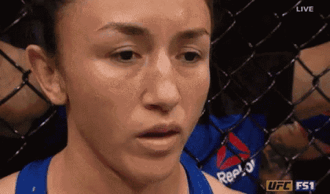 a close up of a woman 's face in a cage with a reebok shirt on .