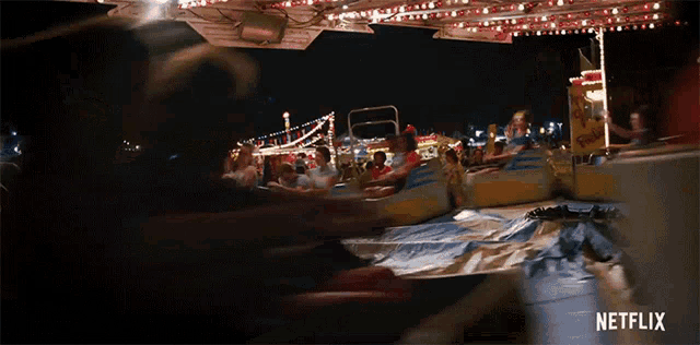 a group of people are riding a roller coaster at a carnival with a netflix logo in the corner