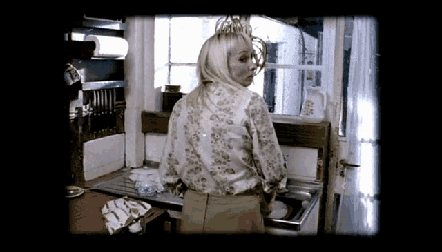 a woman in a floral shirt is standing in front of a sink