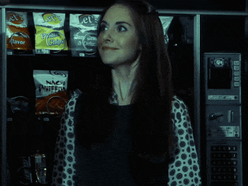 a woman is standing in front of a vending machine that sells let 's potato chips