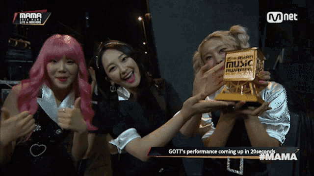 three women holding a trophy that says music on it