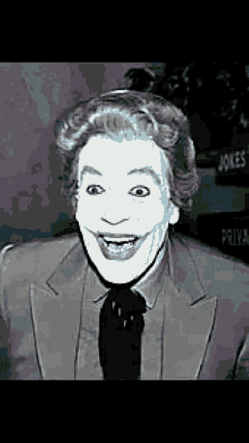 a black and white photo of a man wearing a suit and tie making a joker face .