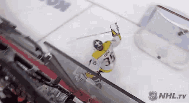 a hockey player is flying through the air while holding a stick in his hand .