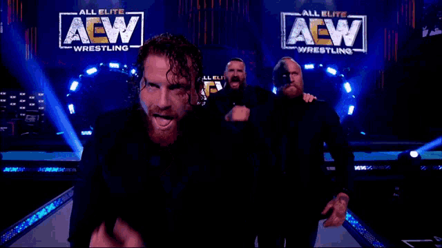a group of men are standing in front of a large screen that says aew dynamite