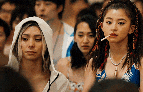 a man in a white hoodie and a woman in a blue bikini smoking a cigarette