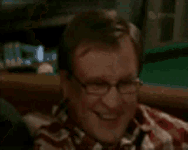 a man is sitting at a pool table holding two cans of soda in his hands .