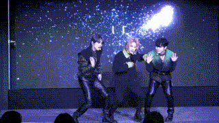 a group of young men are dancing on a stage in front of a crowd .