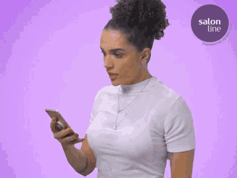 a woman is looking at her phone with a salon line logo in the corner