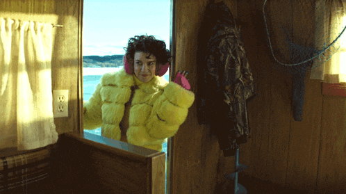 a woman in a yellow fur coat is standing in a room