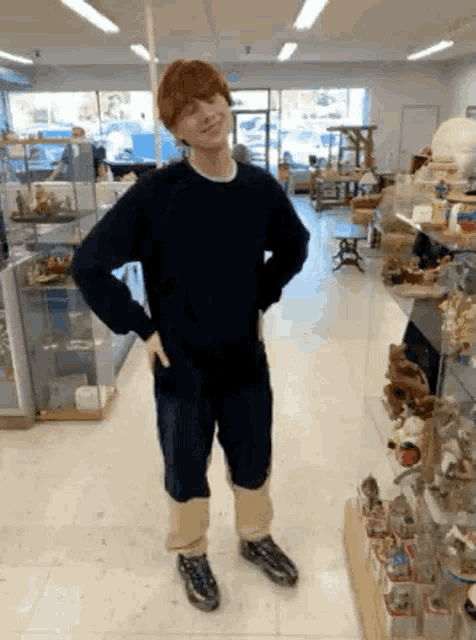 a man is standing in a store with his hands on his hips and wearing a black sweater .