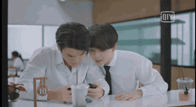 two young men are sitting at a table with a sign that says 10 on it