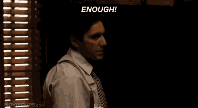 a man in a white shirt and tie is standing in front of a window with the words " enough " written above him