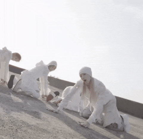 a group of people in white clothes are kneeling on the ground .