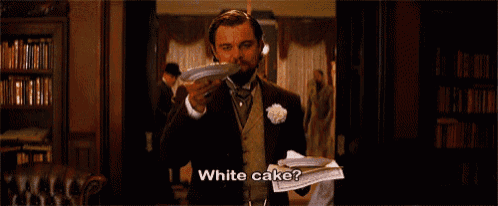 a man in a suit is holding a piece of paper and says white cake