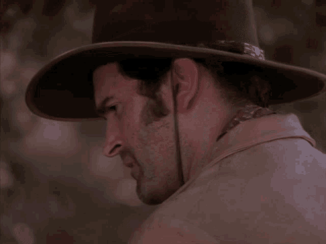 a man wearing a cowboy hat looks at the camera with a surprised look on his face