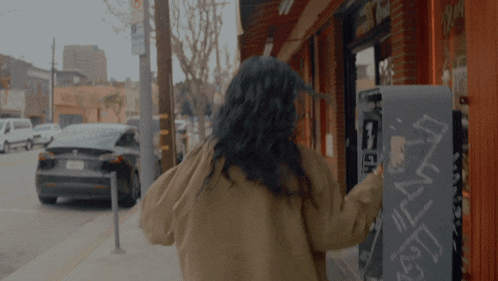 a woman is walking down a sidewalk next to a vending machine that says ' ice cream ' on it