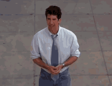 a man is standing on a sidewalk wearing a tie and a white shirt .