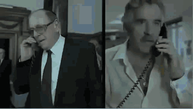 two men in suits and ties are talking on telephones in a room .