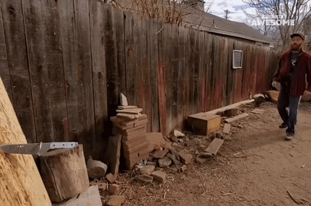 a man walking in front of a wooden fence with awesome written on the bottom