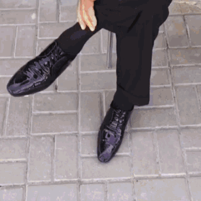 a close up of a person 's feet wearing black shoes